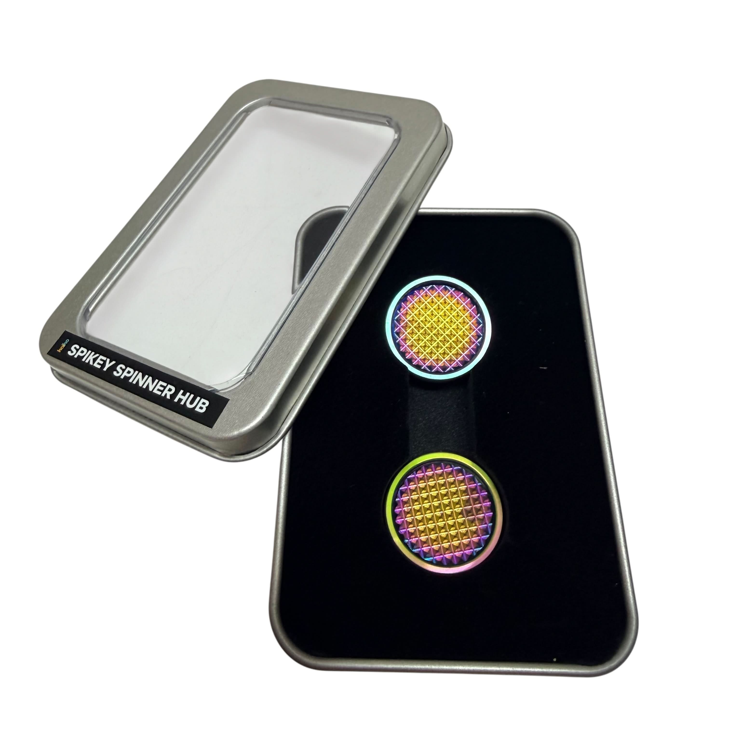 Pair of oil slick Spikey Spinner Hubs displayed in the included window tin